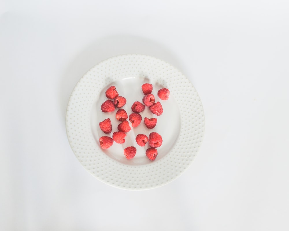 a white plate topped with strawberries on top of a white table
