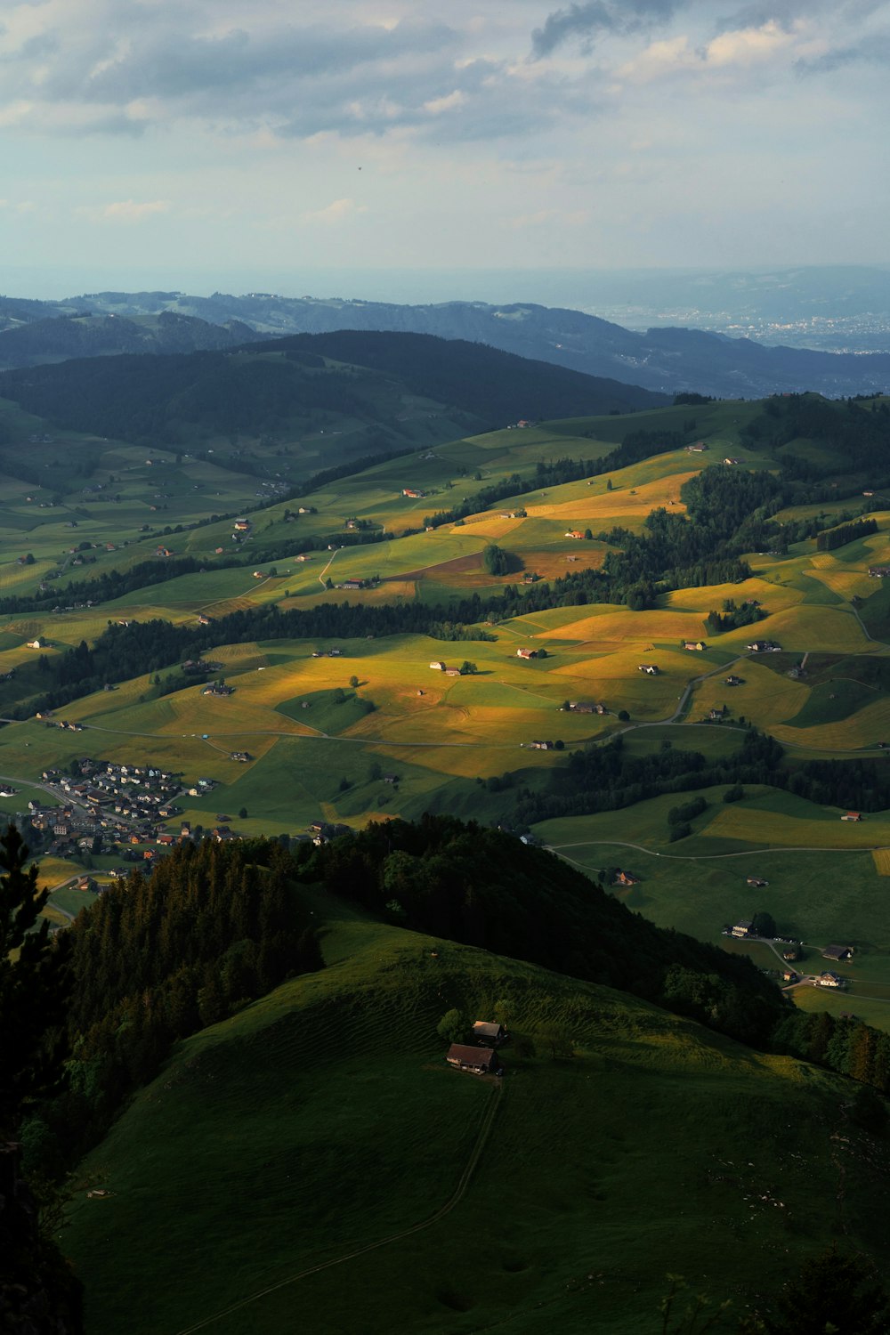 a view of a lush green valley with houses in the distance