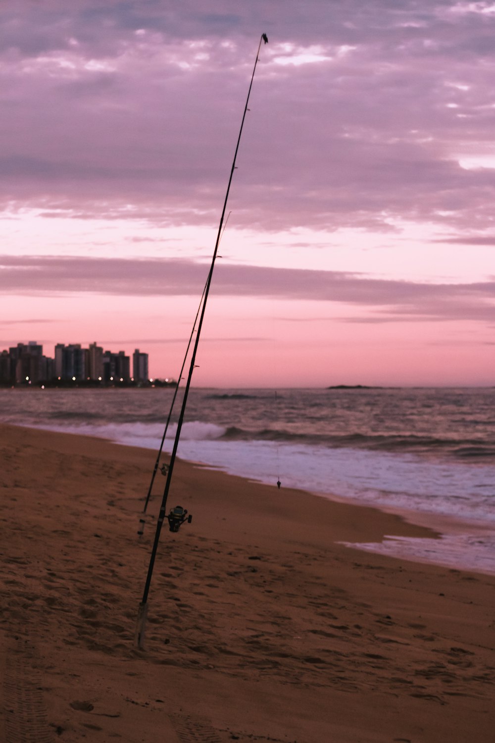 a fishing pole on the beach with a city in the background