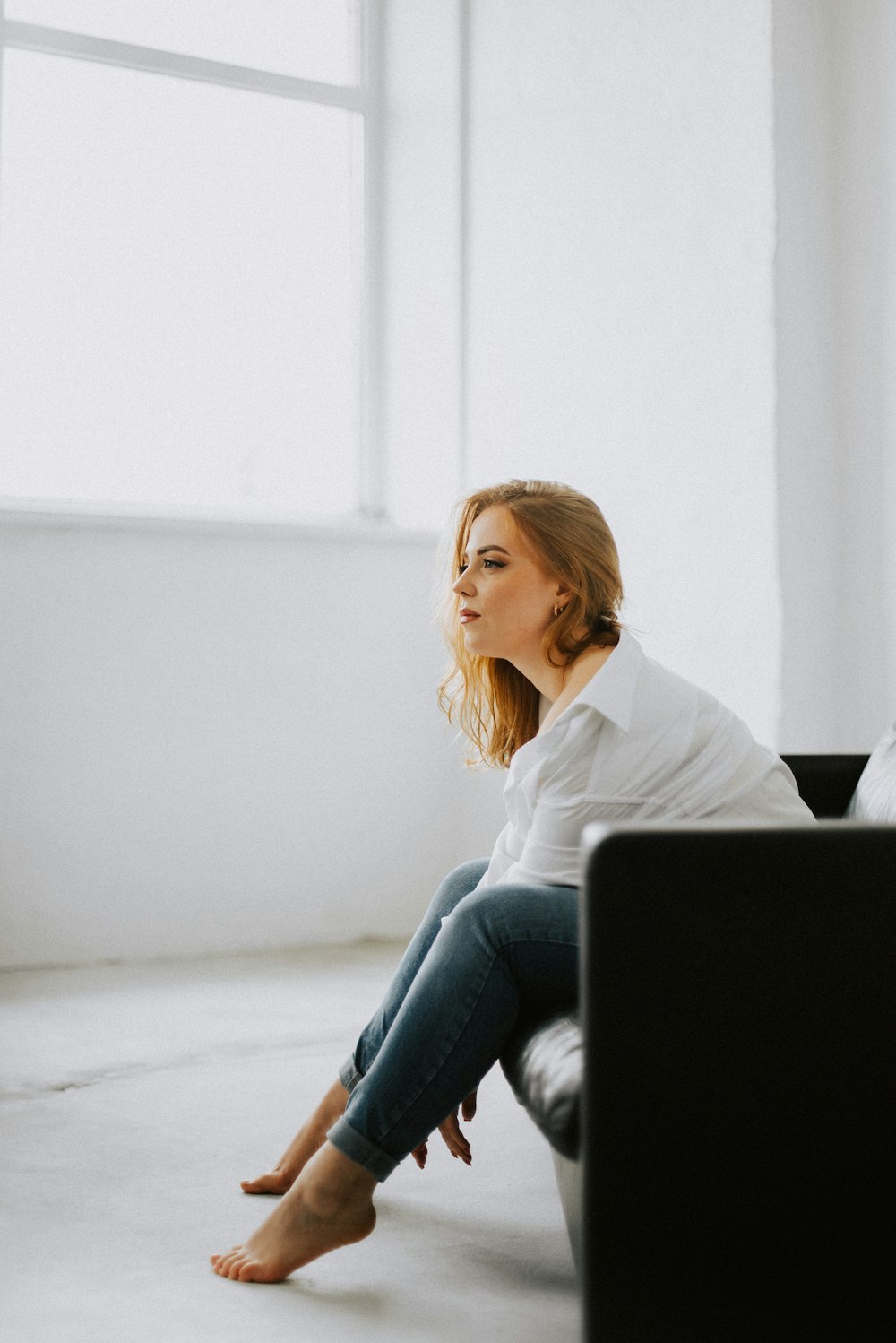 a woman sitting on a couch in a white room