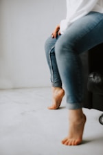 A person demonstrating how to properly wear a knee supporter in a clean, minimalistic setting.