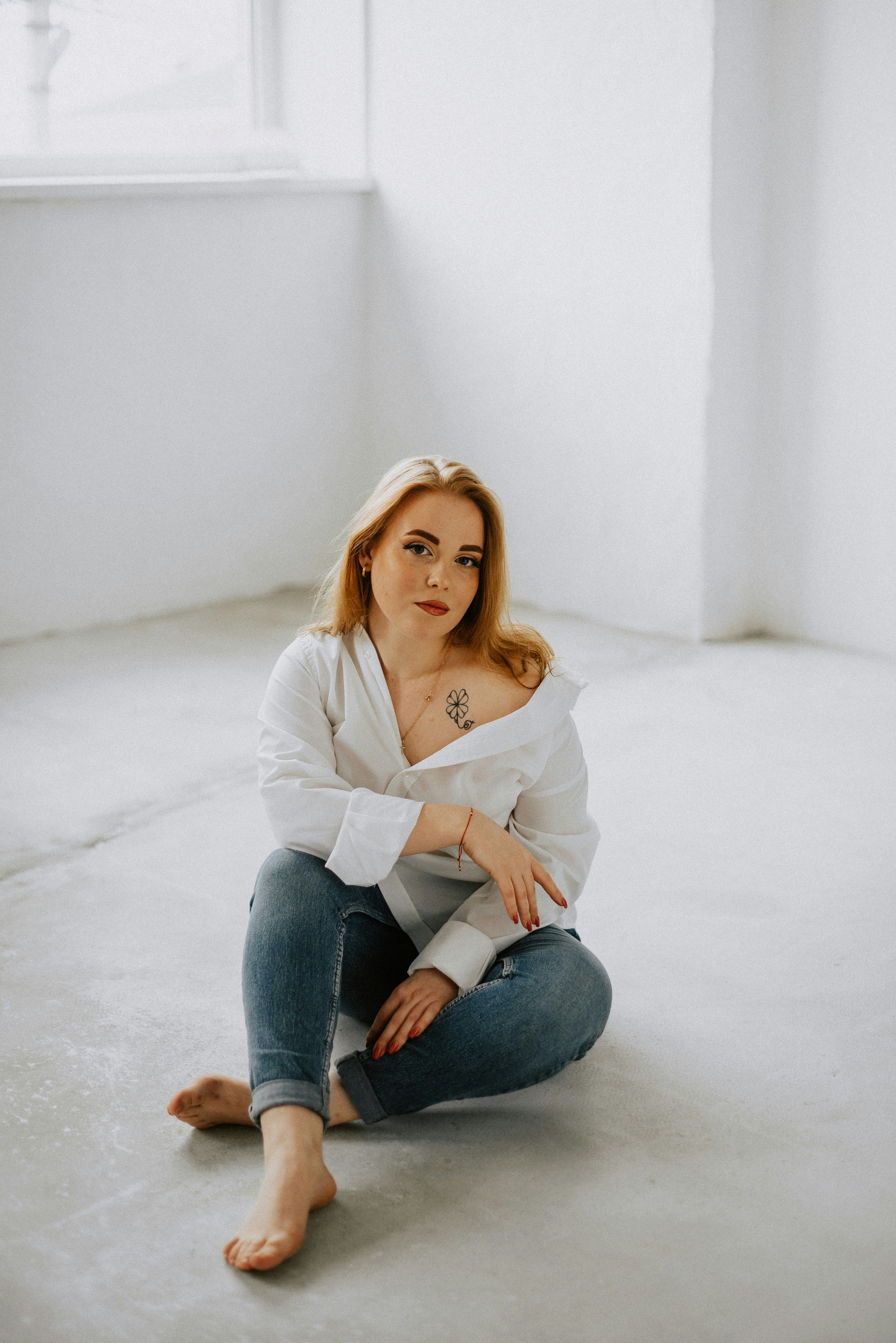 a woman sitting on the floor in a white room