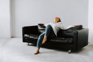 a woman sitting on a black couch in a white room