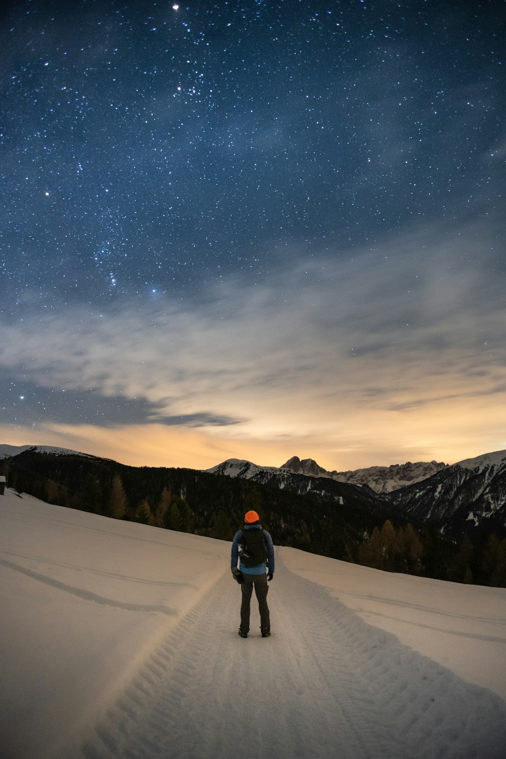 a man standing on top of a snow covered slope under a night sky