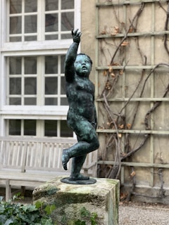 A marble statue showcasing a joyful child standing with arms raised, expressing delight.