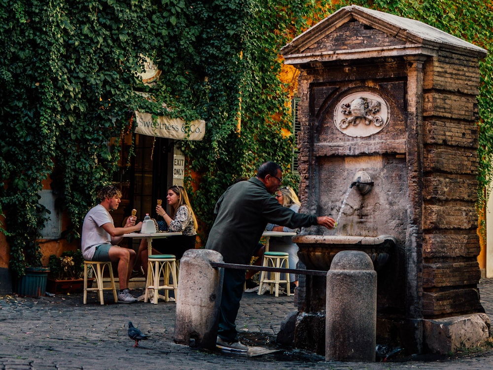 a group of people sitting at a table next to a fountain
