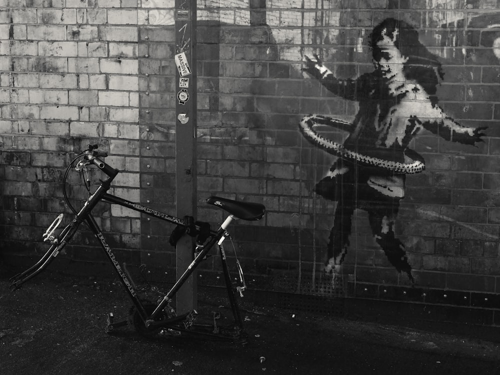 a bicycle parked next to a wall with a painting on it