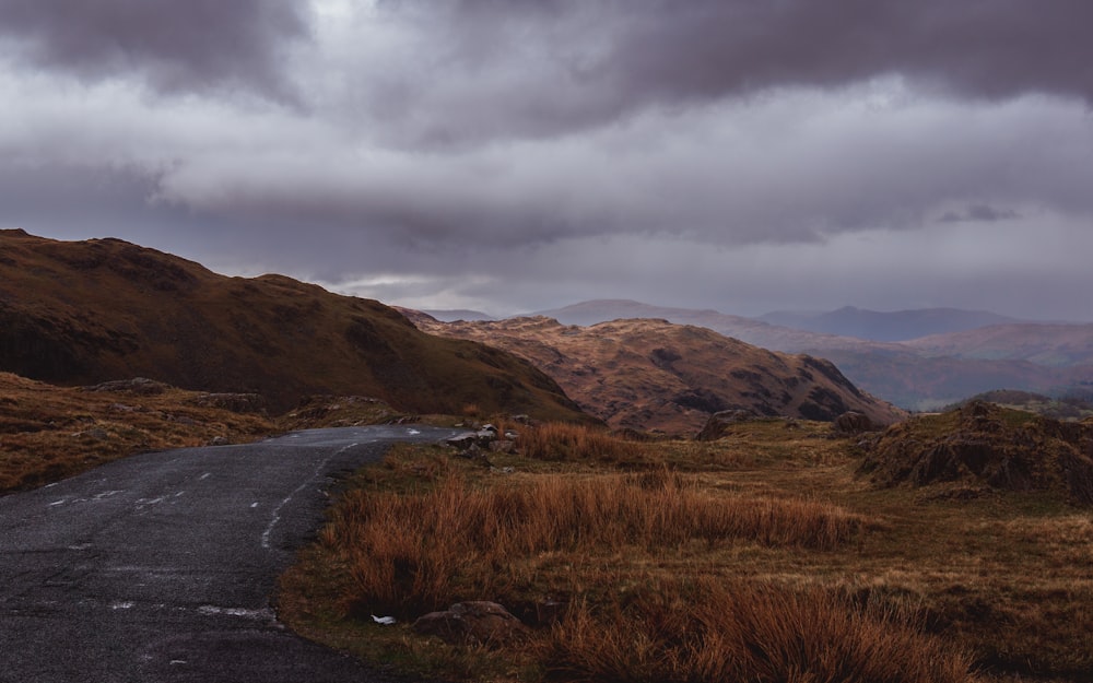 a road in the middle of a field with mountains in the background