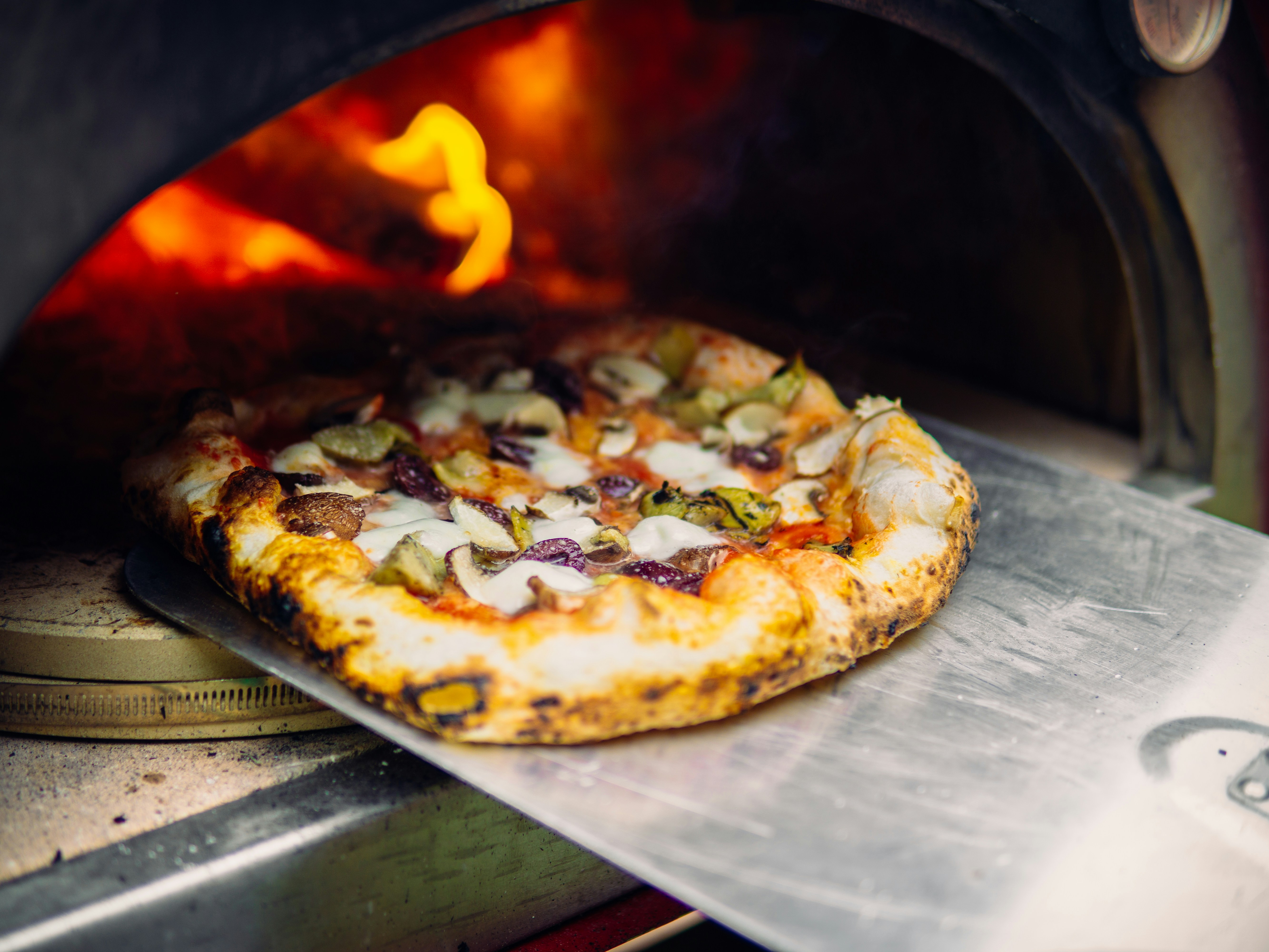 A picture of a freshly cooked pizza in the wood-fire oven.