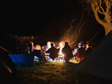 Campfire area surrounded by tents with guests enjoying the evening.