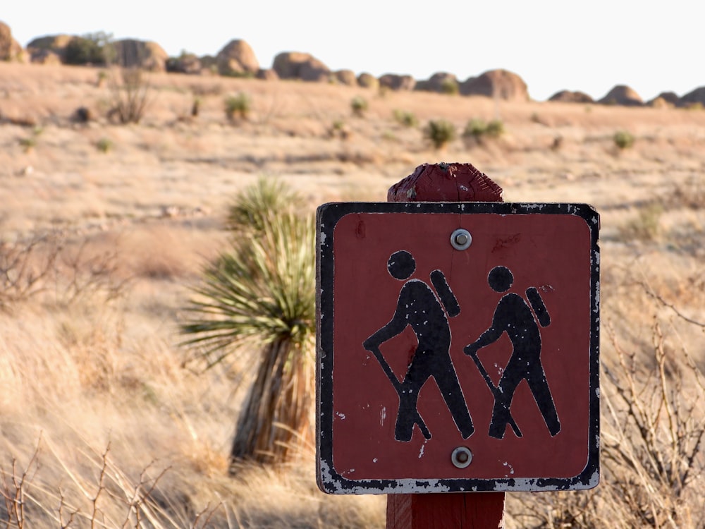 a red and black sign on a pole in a field