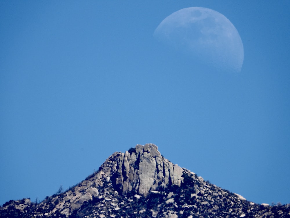 a full moon is seen above a mountain