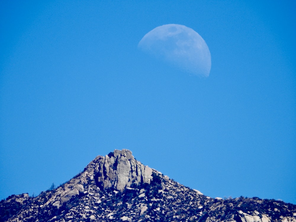 a half moon is seen over a mountain