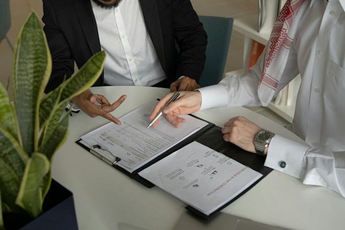 Two people at a table reviewing papers, like a buyer checking rental licenses and code records before closing on a Las Vegas home