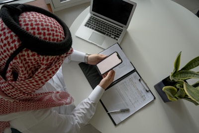 a person sitting at a desk with a laptop and a clipboard
