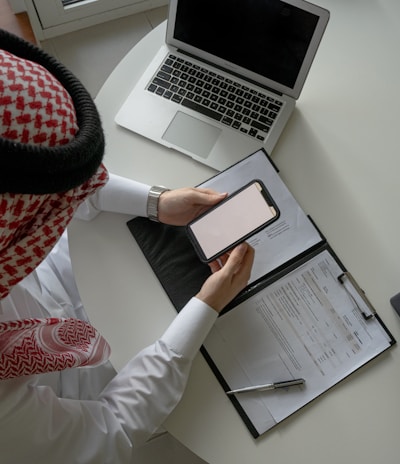 a person sitting at a desk with a laptop and a clipboard