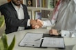 a couple of men shaking hands over a desk