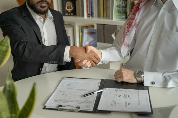 a couple of men shaking hands over a desk