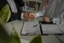 two people shaking hands over a piece of paper