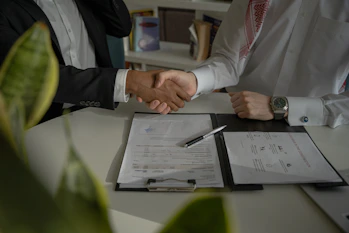 two people shaking hands over a piece of paper