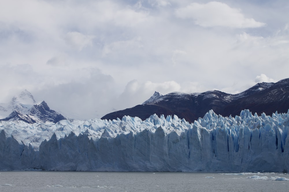 a large glacier with mountains in the background