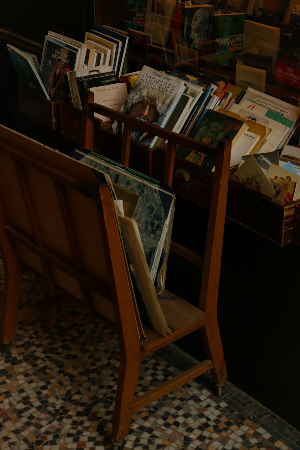 um porta-revistas de madeira cheio de livros em cima de um piso de azulejos
