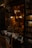 A cozy bookstore display with neatly arranged books and postcards. Warm lighting illuminates the interior, highlighting the vintage decor and a variety of reading materials. Shelves are filled with numerous books and photographs, exuding an inviting and intellectual atmosphere.
