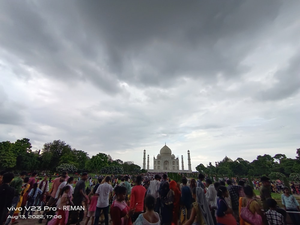 a crowd of people standing in front of a building under a cloudy sky