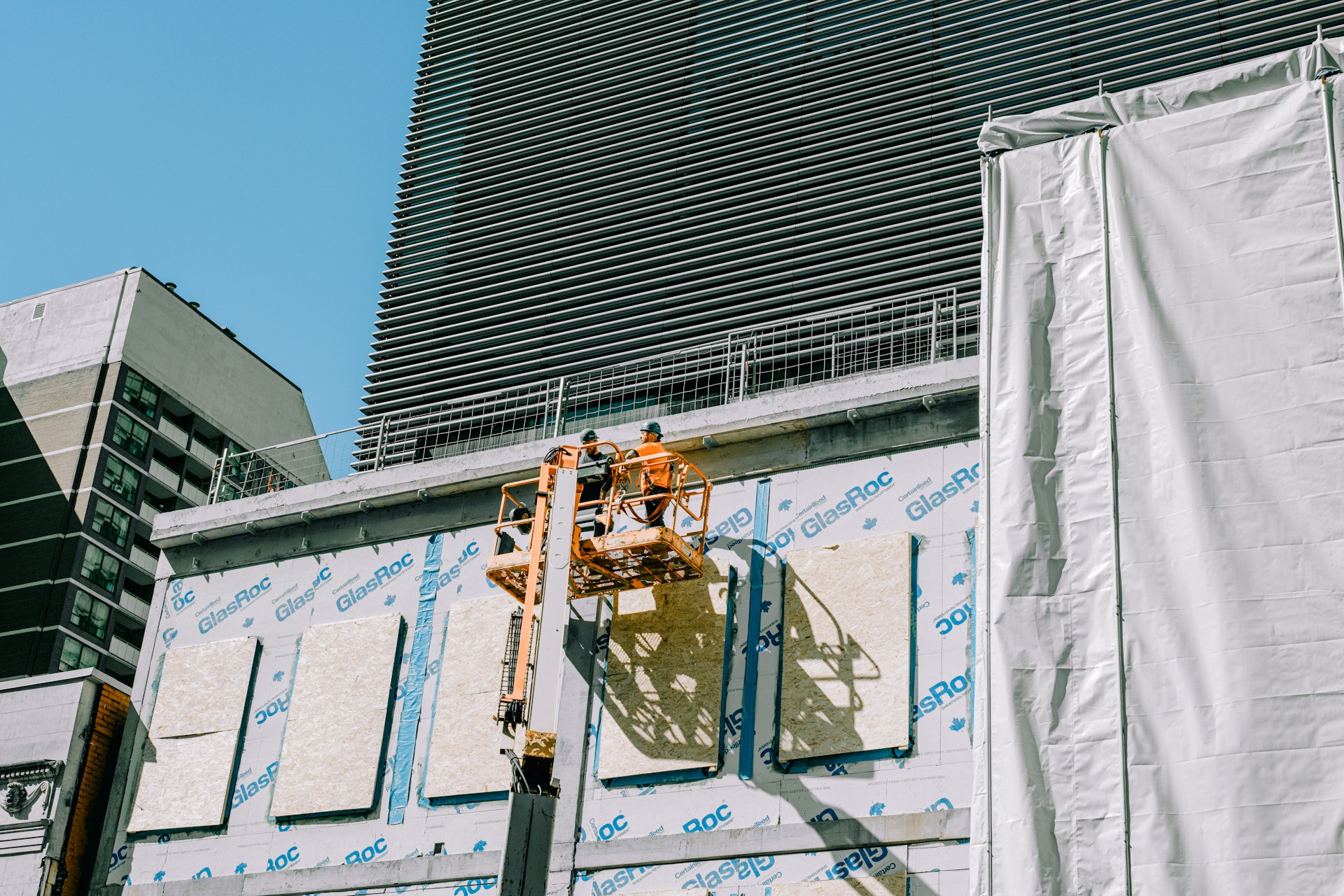 ouvrier posant l isolation thermique par l exterieur sur une facade de batiment ProxiBTP