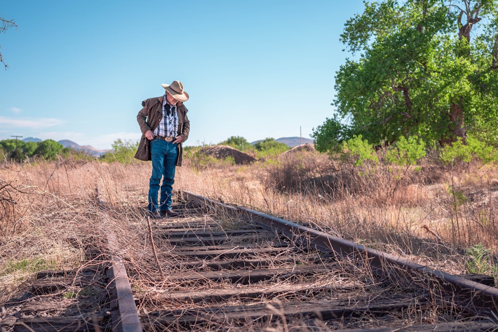 a man standing on a train track in the middle of a field