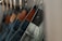 A row of denim jeans hanging from hangers, each featuring a distinct leather patch on the back waistband. The denim is in various shades of blue, with some patches showing brand labels.