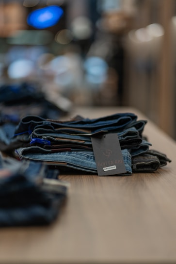 A stylish pair of men's jeans folded neatly on a dark wooden surface with soft lighting.