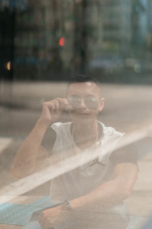 Person wearing sleek malik eyewear outdoors, with a cityscape blurred in the background.