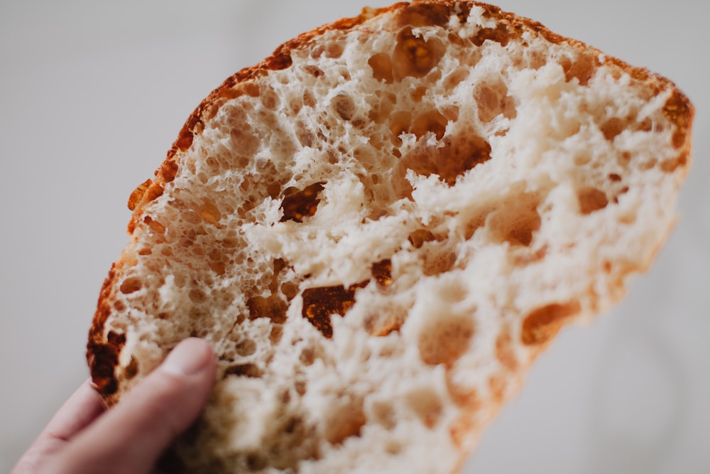 a close up of a person holding a piece of bread