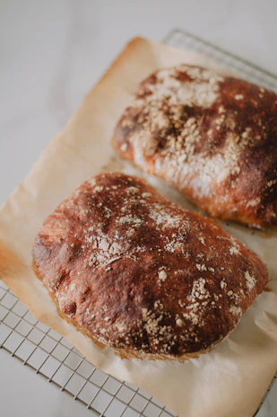 Golden crust breads cooling on a rustic wire rack with flour dusting.