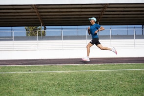 An athlete wearing a full black sports outfit with white and yellow accents, running on a track.