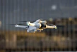 High-tech drones flying over a cityscape at dusk with blue lighting accents
