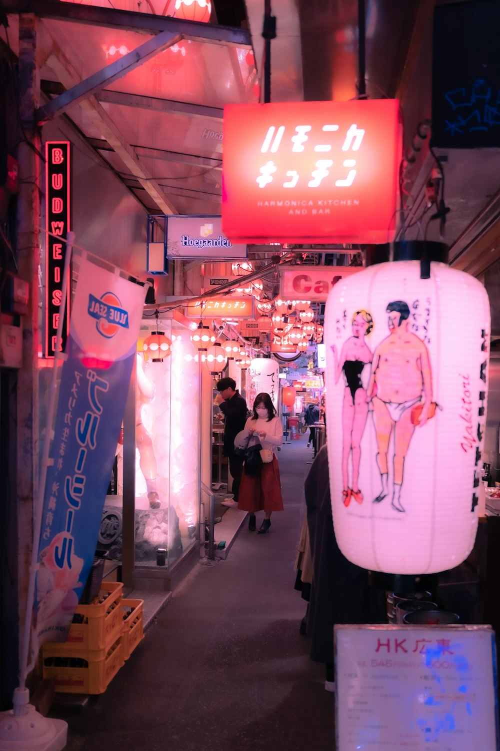 a woman walking down a street next to a neon sign