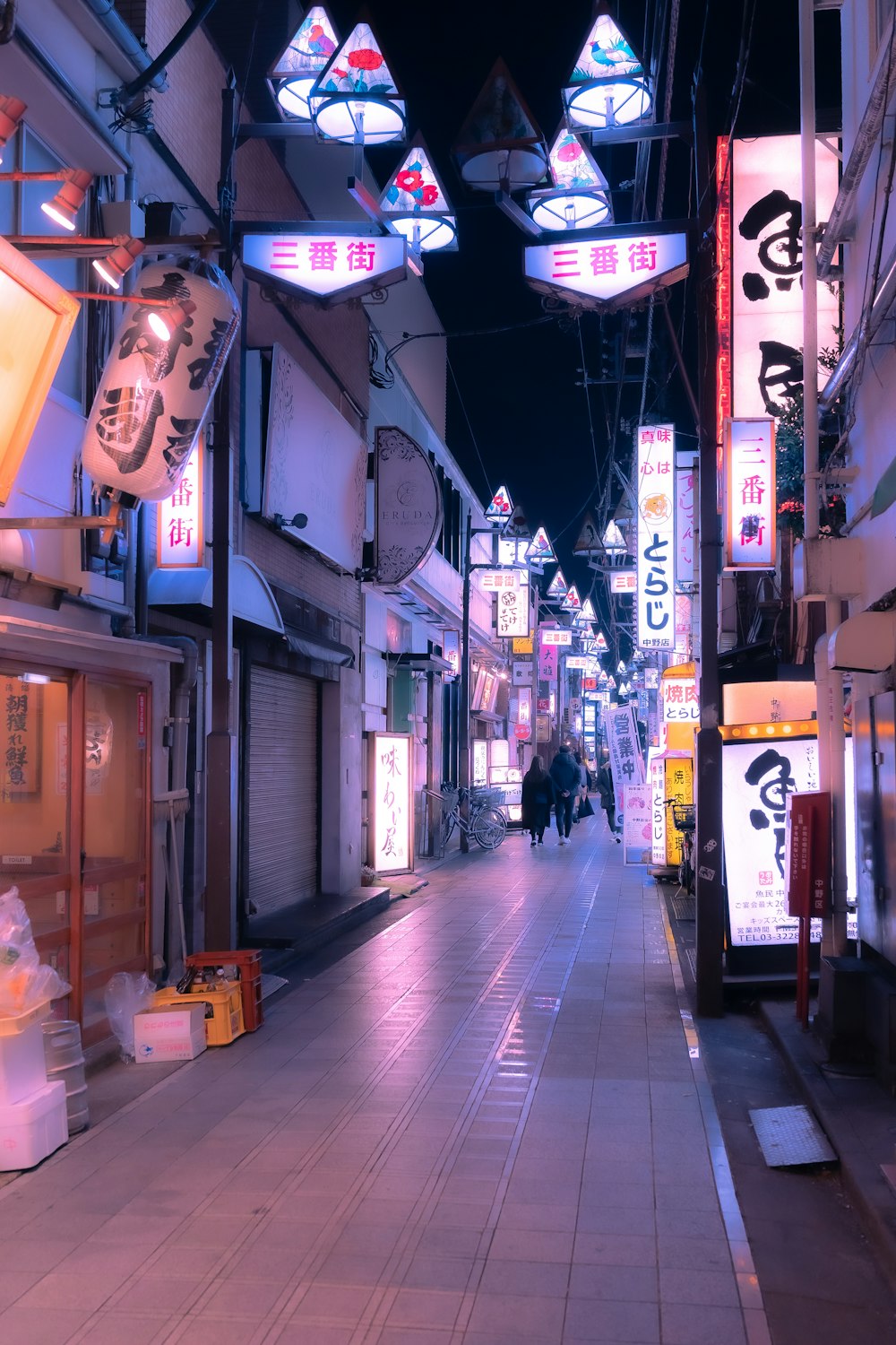 a city street at night with people walking down it