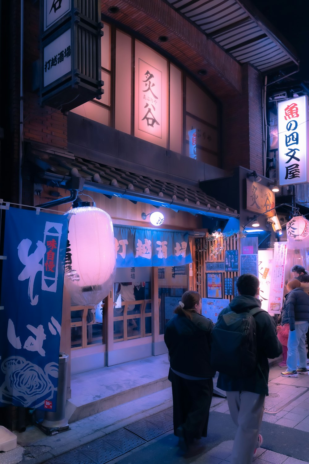 a group of people walking down a street at night