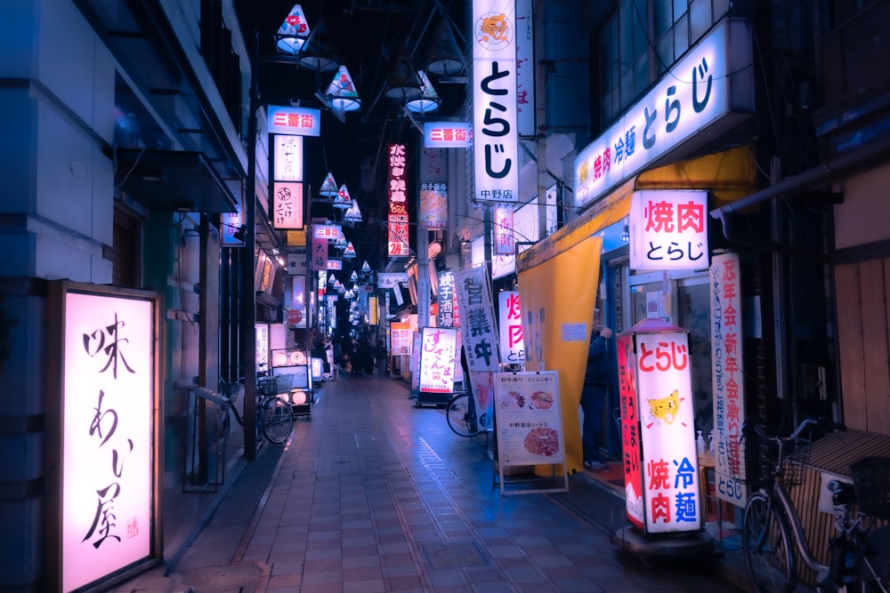 a narrow city street at night with neon signs