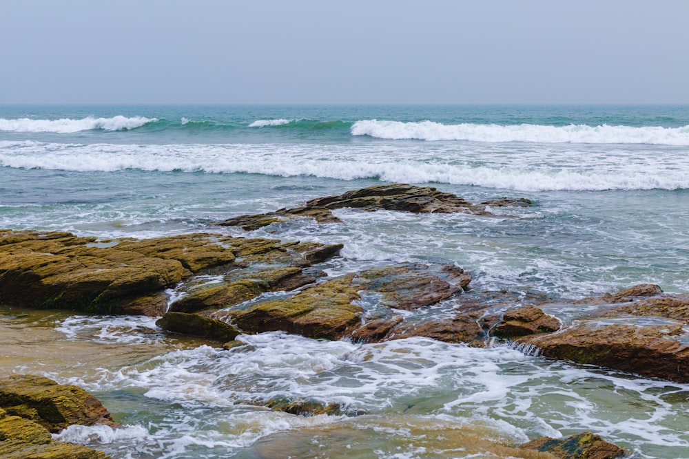 a person standing on rocks near the ocean