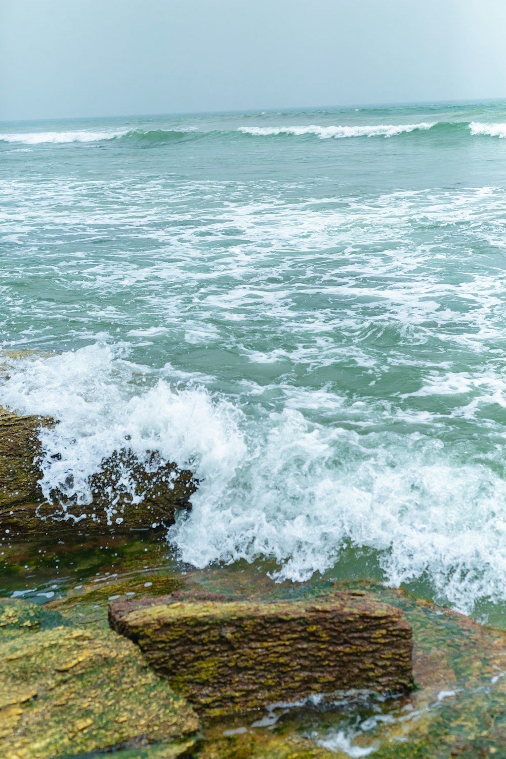 a person standing on a rock next to the ocean