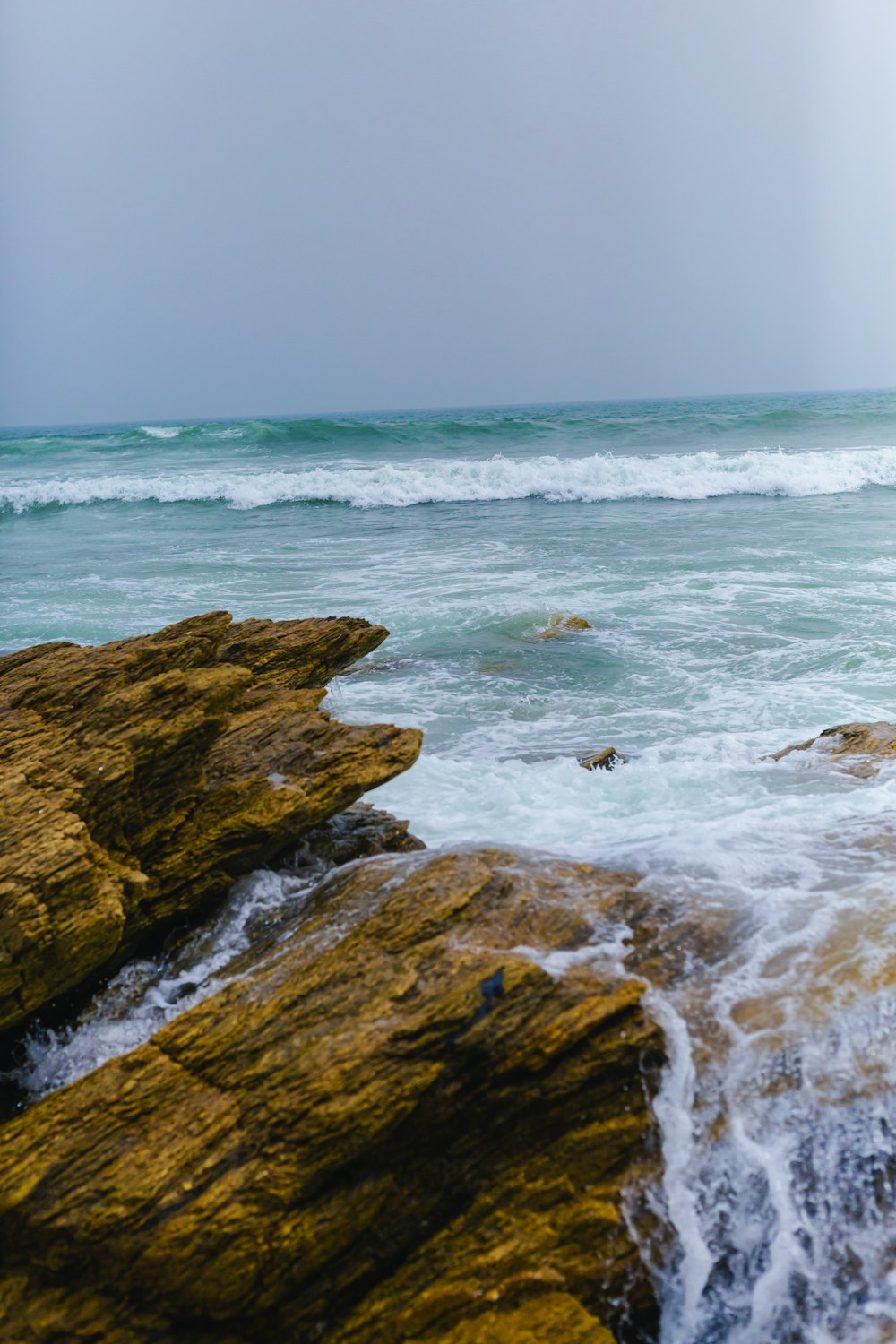 a man standing on top of a rock next to the ocean