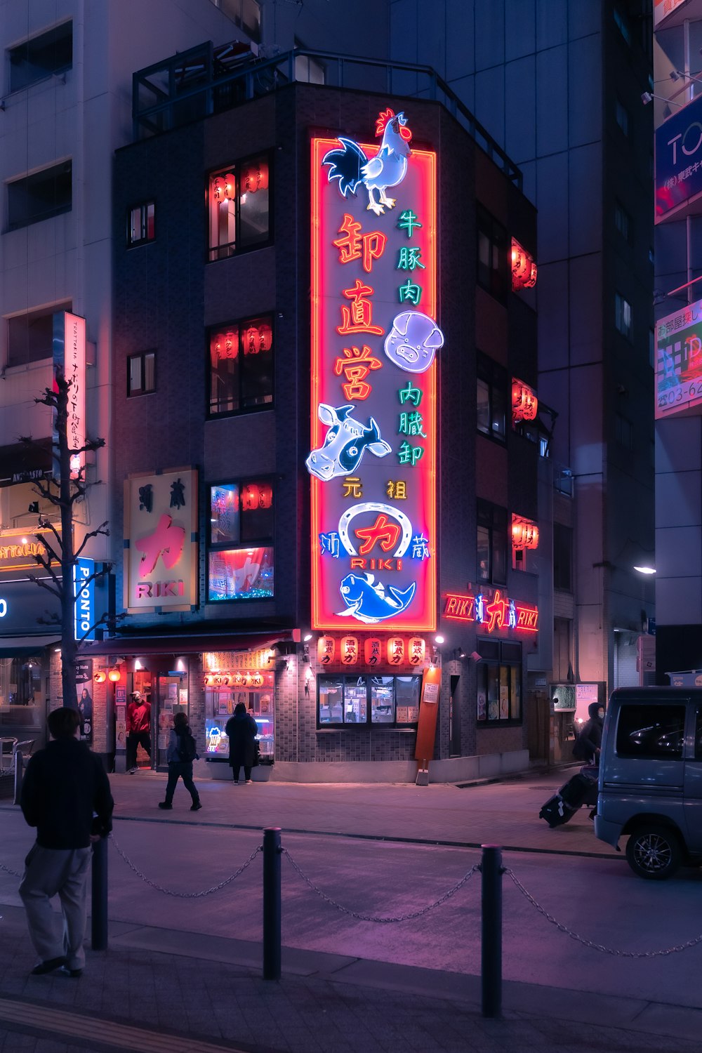 a city street at night with people walking on the sidewalk