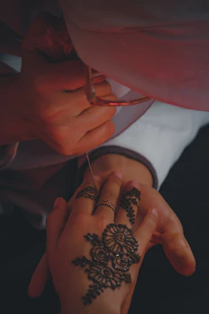 Hands creating delicate henna tattoo with a fine applicator bottle.