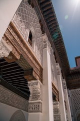 Intricately designed architectural façade featuring detailed geometric patterns and carvings. The ornate archways and columns showcase traditional motifs, with sunlight casting soft contrasts against the structure.