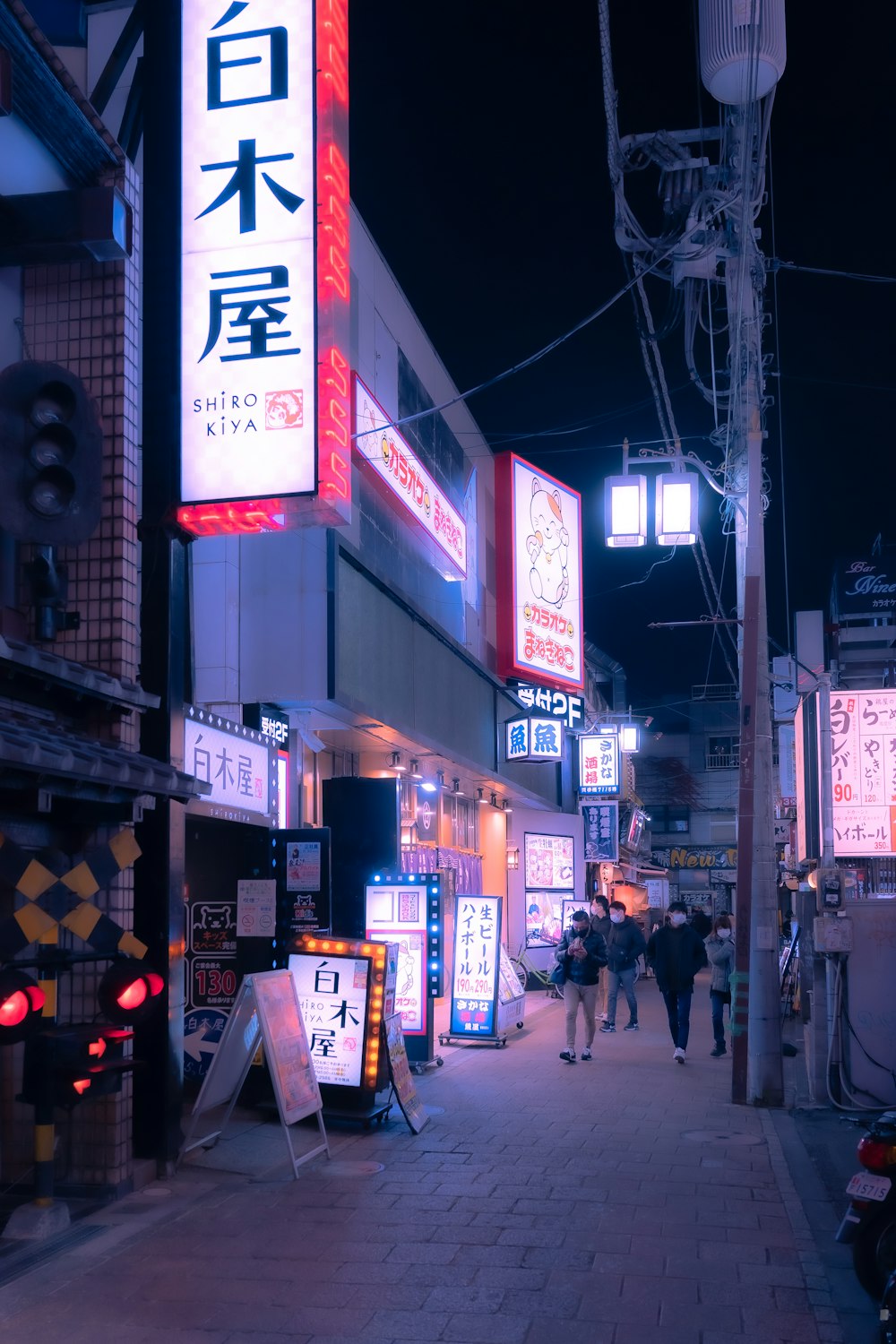 a city street at night with people walking on the sidewalk