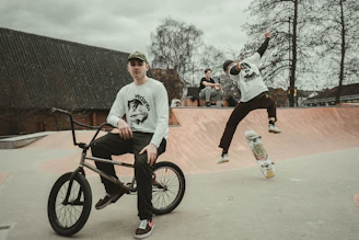 a man riding a bike next to another man on a skateboard
