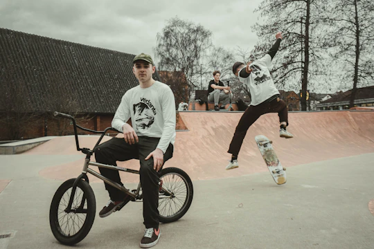 a man riding a bike next to another man on a skateboard